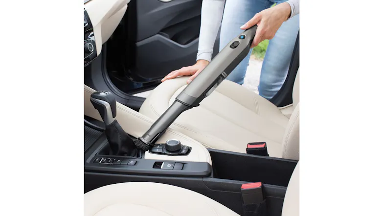 The handheld vacuum cleaner being used to maintain a car interior The handheld vacuum cleaner being used to maintain a car interior