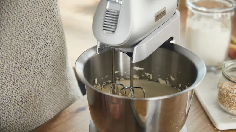 Close-up of the mixer beating batter inside the stainless-steel bowl on the stand Close-up of the mixer beating batter inside the stainless-steel bowl on the stand