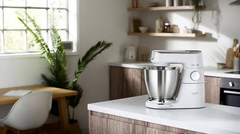 Kenwood Titanium Chef Baker XL stand mixer in pearl white displayed on a kitchen island Kenwood Titanium Chef Baker XL stand mixer in pearl white displayed on a kitchen island