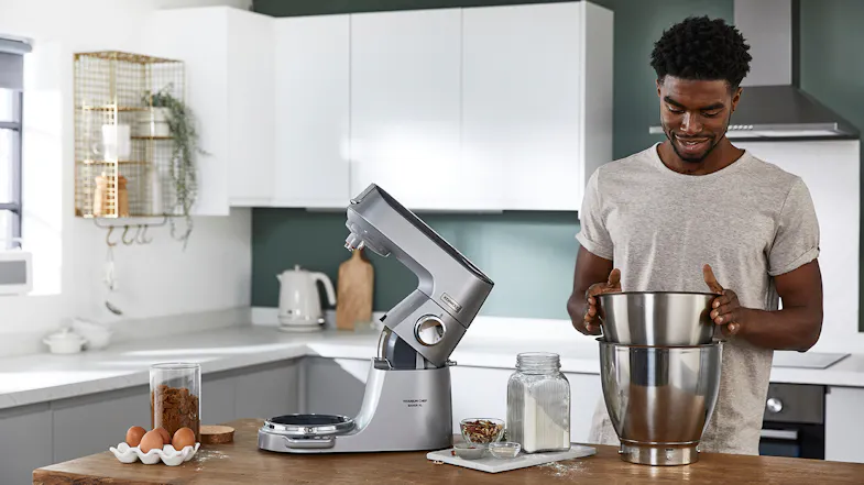 Silver Kenwood Titanium Chef Baker XL stand mixer with its head raised, shown beside ingredients Silver Kenwood Titanium Chef Baker XL stand mixer with its head raised, shown beside ingredients