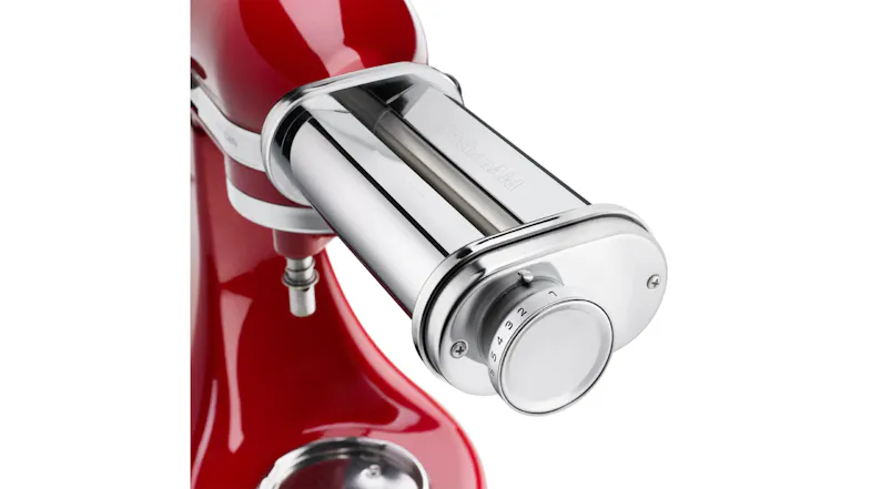 Close-up of the KitchenAid pasta roller attachment showing the adjustable thickness dial and rollers Close-up of the KitchenAid pasta roller attachment showing the adjustable thickness dial and rollers