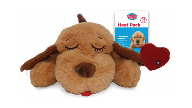 Sleeping plush Snuggle Puppy toy shown with disposable heat pack packaging and a red heart-shaped warming pad Sleeping plush Snuggle Puppy toy shown with disposable heat pack packaging and a red heart-shaped warming pad