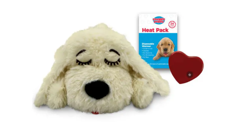 Plush golden Snuggle Puppy dog toy with a heat pack and a small red heart-shaped warming device beside it Plush golden Snuggle Puppy dog toy with a heat pack and a small red heart-shaped warming device beside it