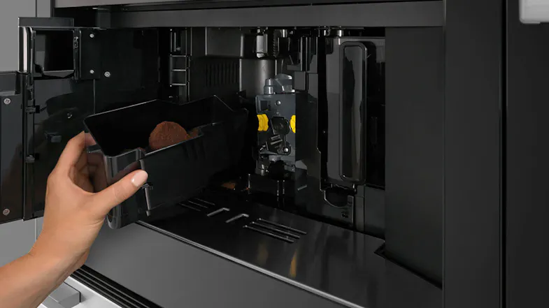 Hands installing a component inside the coffee machine’s compartment. Hands installing a component inside the coffee machine’s compartment.
