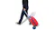 A person pulling the red luggage trolley like a suitcase, with the scooter folded up behind it A person pulling the red luggage trolley like a suitcase, with the scooter folded up behind it