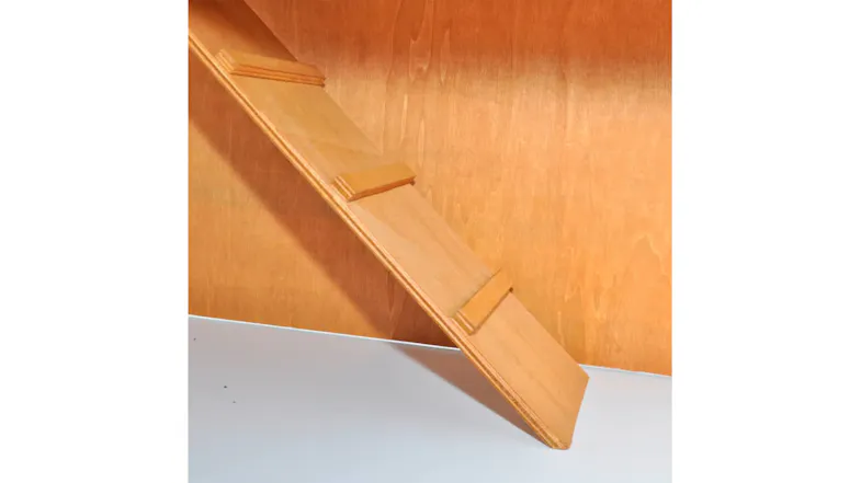 Close-up of a wooden ramp with small traction slats inside a pet hutch, leading from the white floor to the upper level Close-up of a wooden ramp with small traction slats inside a pet hutch, leading from the white floor to the upper level