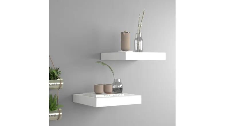 Two white floating shelves mounted on a wall and styled with decorative objects Two white floating shelves mounted on a wall and styled with decorative objects