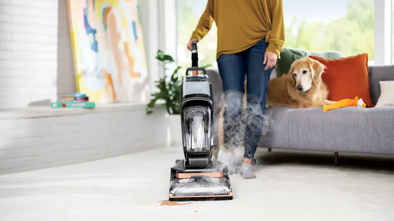 A person uses the Bissell Revolution Hydrosteam cleaner on a carpet, with steam rising from the cleaning head A person uses the Bissell Revolution Hydrosteam cleaner on a carpet, with steam rising from the cleaning head