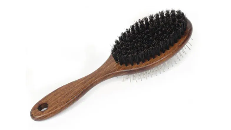 A wooden hairbrush with dark bristles on one side and metal pins on the other A wooden hairbrush with dark bristles on one side and metal pins on the other