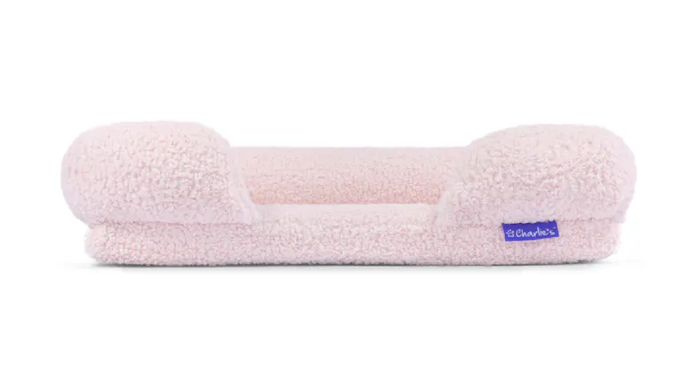 A pink fleece pet sofa with a low centre and raised cushioned sides A pink fleece pet sofa with a low centre and raised cushioned sides