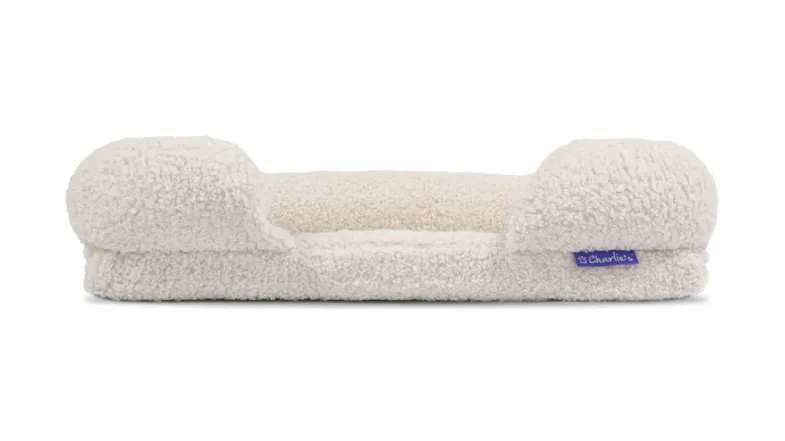A cream fleece pet sofa with a low centre and raised cushioned sides A cream fleece pet sofa with a low centre and raised cushioned sides