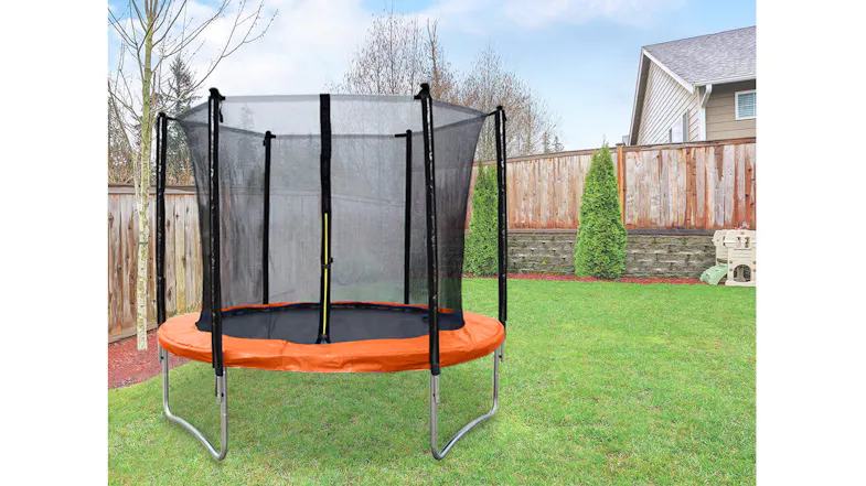 A smaller trampoline with an orange safety pad and a black net enclosure on a green lawn in a suburban area A smaller trampoline with an orange safety pad and a black net enclosure on a green lawn in a suburban area