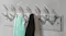 Chrome wall-mounted coat rack with six curved hooks holding towels and clothing Chrome wall-mounted coat rack with six curved hooks holding towels and clothing