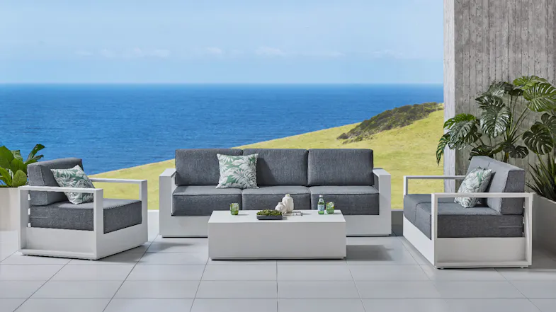 A white Monaco outdoor lounge setting with two armchairs and a three‑seater sofa featuring grey cushions A white Monaco outdoor lounge setting with two armchairs and a three‑seater sofa featuring grey cushions