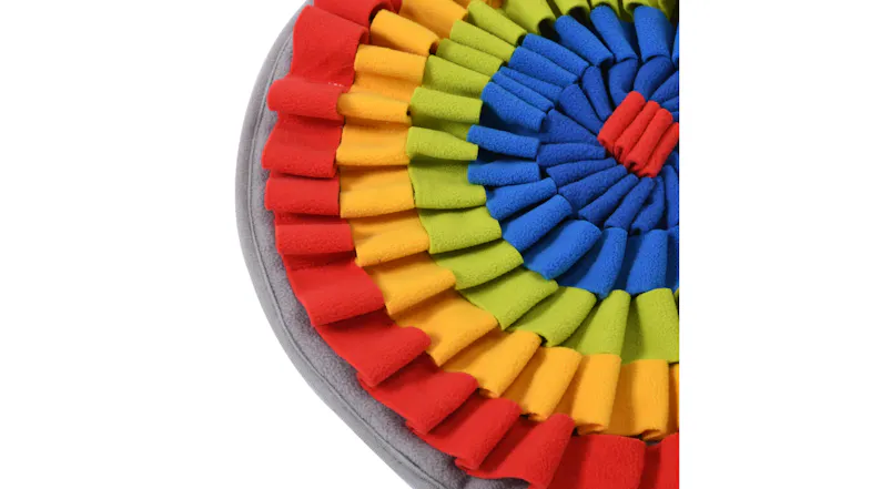 Close-up of a round mat with layered red, yellow, green, and blue fabric strips arranged in concentric rings Close-up of a round mat with layered red, yellow, green, and blue fabric strips arranged in concentric rings