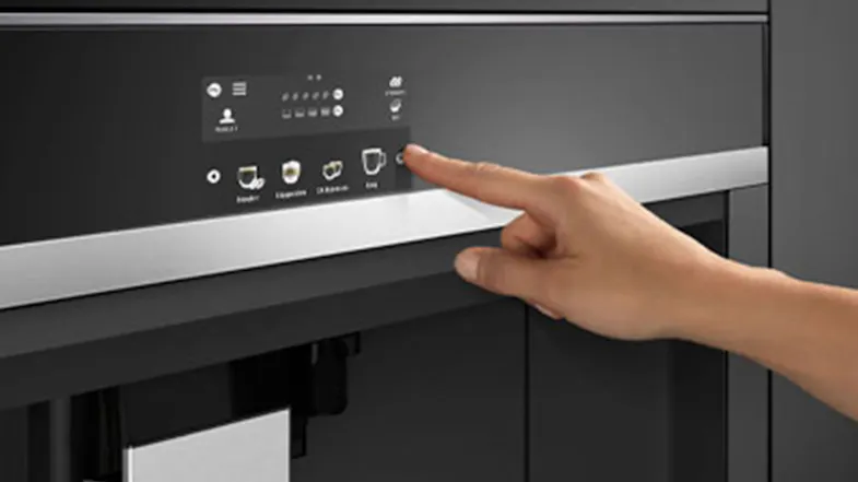 Hand pressing a button on the coffee machine’s control panel. Hand pressing a button on the coffee machine’s control panel.