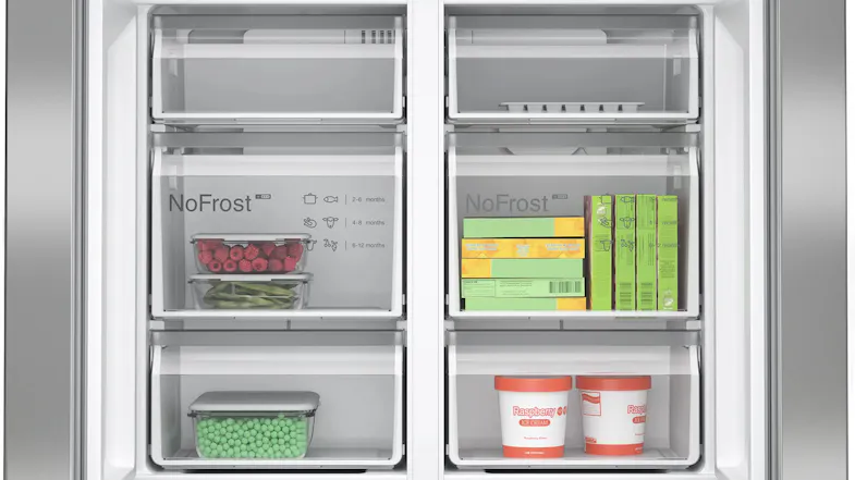 Close-up of freezer drawers labelled NoFrost, storing frozen raspberries, peas, and two tubs of raspberry ice cream Close-up of freezer drawers labelled NoFrost, storing frozen raspberries, peas, and two tubs of raspberry ice cream