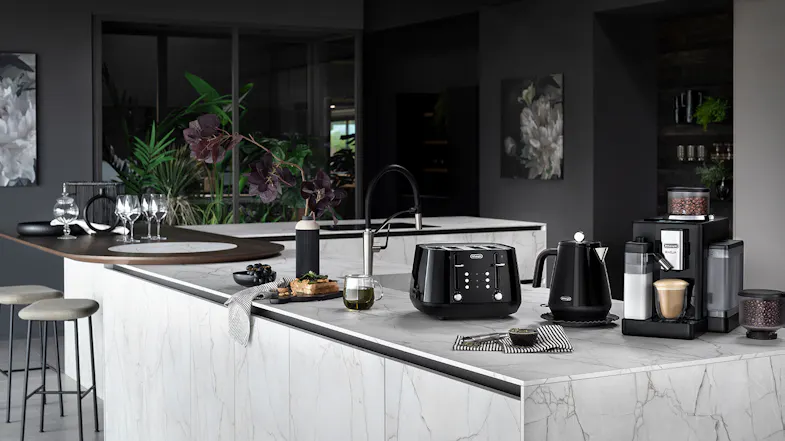 Modern kitchen with marble counters featuring De’Longhi Onyx Black espresso machine, toaster, kettle, and coffee accessories Modern kitchen with marble counters featuring De’Longhi Onyx Black espresso machine, toaster, kettle, and coffee accessories