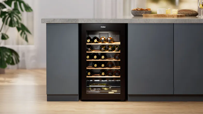 Haier 300 Series Wine Fridge installed under a kitchen counter, stocked with wine bottles and lit internally Haier 300 Series Wine Fridge installed under a kitchen counter, stocked with wine bottles and lit internally
