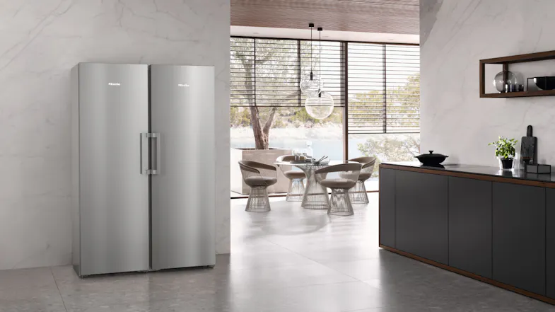 Two Miele silver smart fridges placed side by side in a contemporary kitchen with marble walls Two Miele silver smart fridges placed side by side in a contemporary kitchen with marble walls