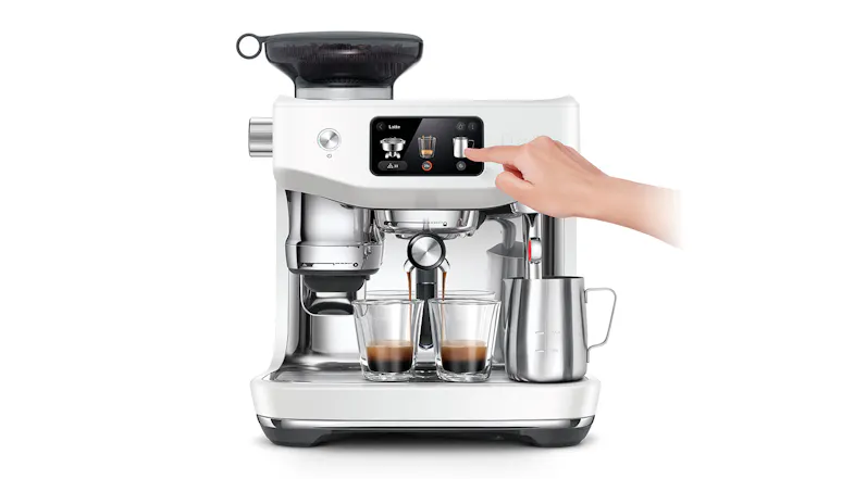 A hand is pressing a button on a stainless steel espresso machine as two glasses fill with espresso A hand is pressing a button on a stainless steel espresso machine as two glasses fill with espresso