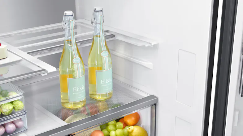 Close-up of glass bottles on a clear shelf inside a fridge Close-up of glass bottles on a clear shelf inside a fridge