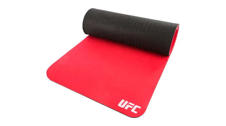 A partially rolled red UFC exercise mat showcasing its thick, ribbed black backing A partially rolled red UFC exercise mat showcasing its thick, ribbed black backing