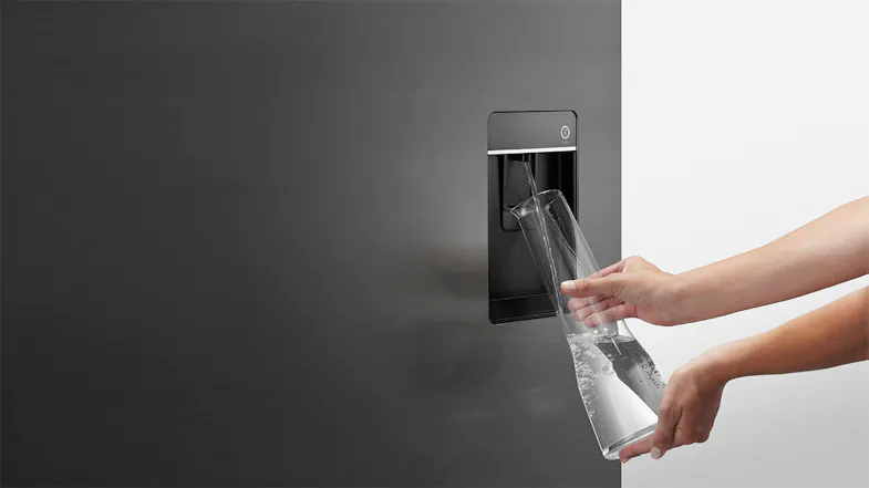 Close-up of the Fisher & Paykel Series 7 fridge water dispenser with a person filling a tall glass carafe Close-up of the Fisher & Paykel Series 7 fridge water dispenser with a person filling a tall glass carafe