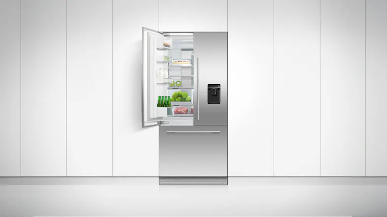 The fridge freezer positioned on a clean white wall with one of its doors opened The fridge freezer positioned on a clean white wall with one of its doors opened