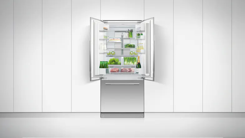 The fridge freezer positioned on a clean white wall with both of its doors opened The fridge freezer positioned on a clean white wall with both of its doors opened