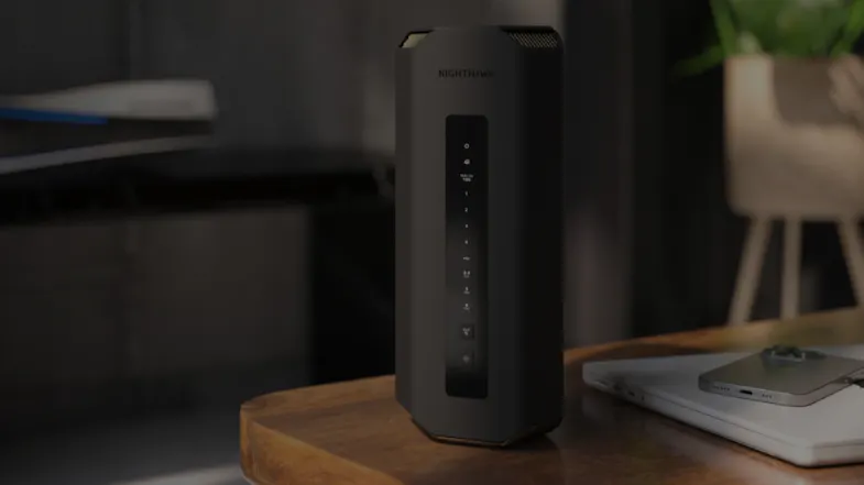 Black tower-style router sitting on a dark wooden desk in a modern home office setting Black tower-style router sitting on a dark wooden desk in a modern home office setting