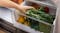 A hand opening the Haier Humidity Zone bin to access fresh vegetables A hand opening the Haier Humidity Zone bin to access fresh vegetables