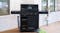 The BBQ is positioned on a wooden deck with the hood closed. The unit features four control knobs and storage The BBQ is positioned on a wooden deck with the hood closed. The unit features four control knobs and storage