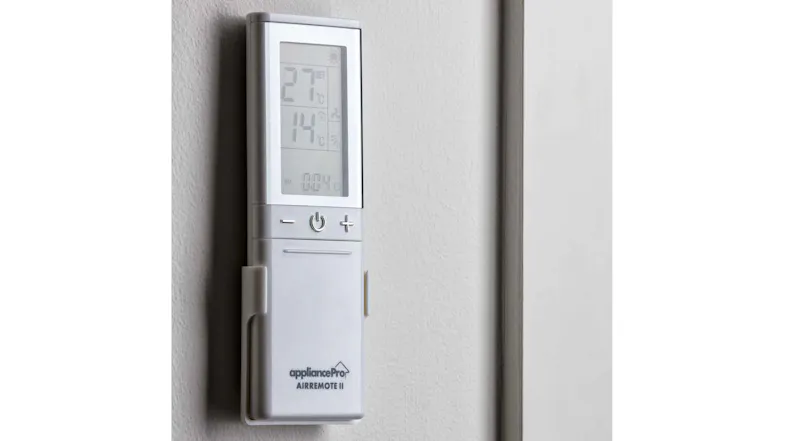 AAirmote II universal air conditioner remote mounted on a wall holder beside a doorway AAirmote II universal air conditioner remote mounted on a wall holder beside a doorway