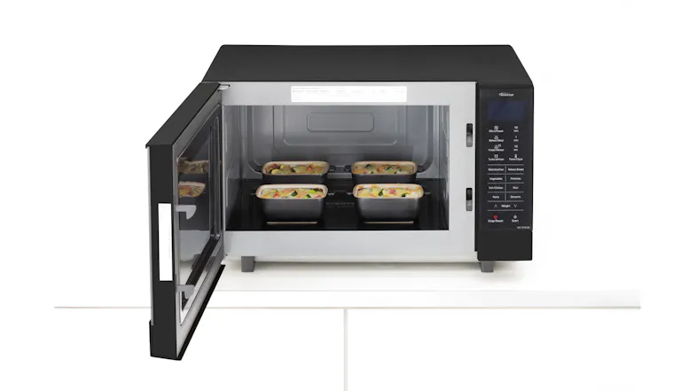 A flatbed inverter microwave with the door open, showing four small dishes of food inside the cooking chamber A flatbed inverter microwave with the door open, showing four small dishes of food inside the cooking chamber