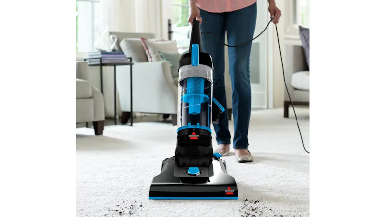 A person vacuuming dirt from a light-colored carpet with an upright vacuum A person vacuuming dirt from a light-colored carpet with an upright vacuum