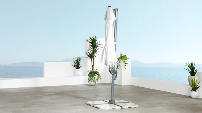 The Pegasus umbrella is shown closed, with the white canopy wrapped around the frame and supported by a weighted base. The Pegasus umbrella is shown closed, with the white canopy wrapped around the frame and supported by a weighted base.