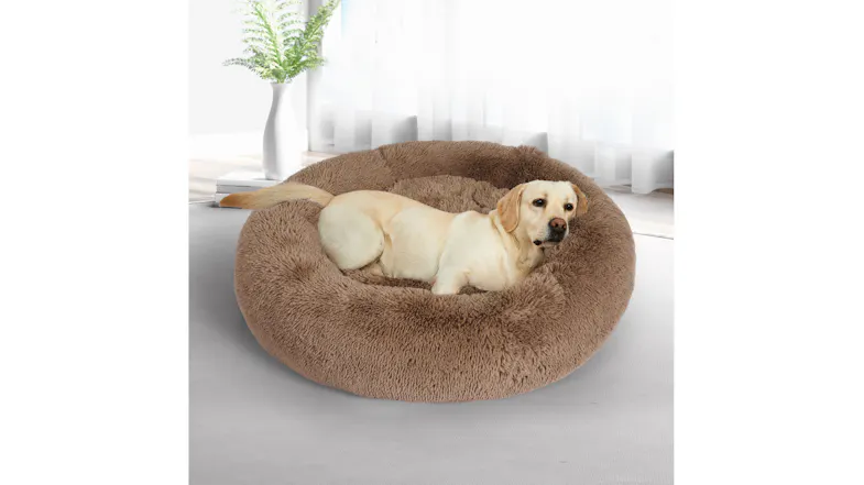 A light-coloured dog is lying comfortably in a round PaWz Fluffy pet bed indoors A light-coloured dog is lying comfortably in a round PaWz Fluffy pet bed indoors