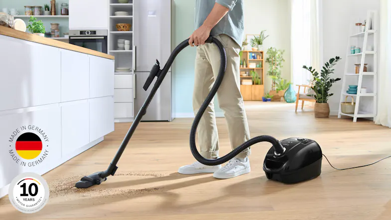 A view of the vacuum being used to clean the floor of a brightly lit home A view of the vacuum being used to clean the floor of a brightly lit home