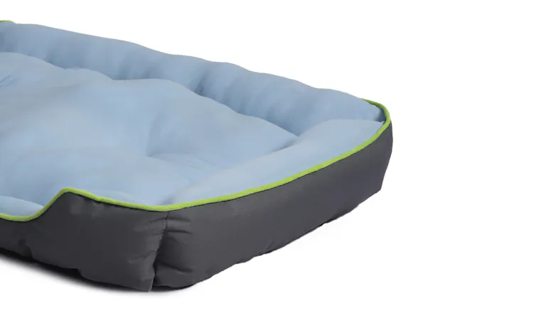 Close-up of a blue cushioned pet bed with grey sides and green trim Close-up of a blue cushioned pet bed with grey sides and green trim