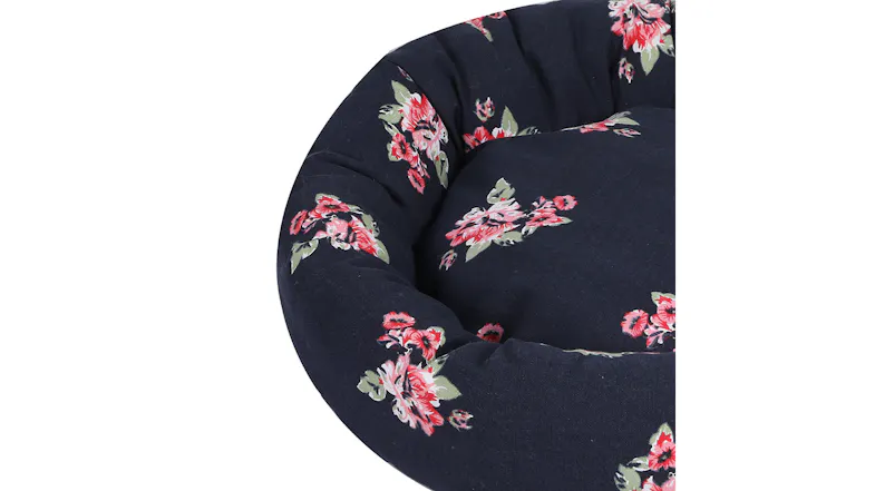 A close-up of a round navy pet bed with floral print and cushioned sides A close-up of a round navy pet bed with floral print and cushioned sides
