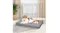 A brown and white cat is relaxing on a grey fluffy pet mat in a bright room with curtains and potted plants A brown and white cat is relaxing on a grey fluffy pet mat in a bright room with curtains and potted plants