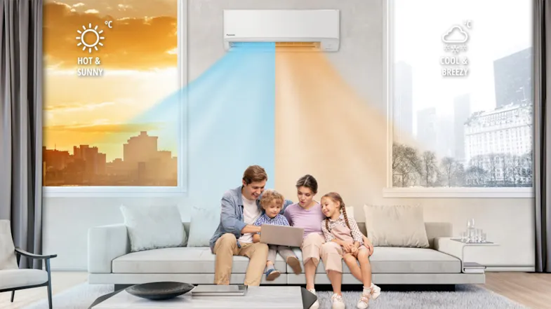 A family sits on a sofa under a Panasonic air conditioner with dual airflow; the left window shows the hot sun, while the right shows a cool breeze A family sits on a sofa under a Panasonic air conditioner with dual airflow; the left window shows the hot sun, while the right shows a cool breeze