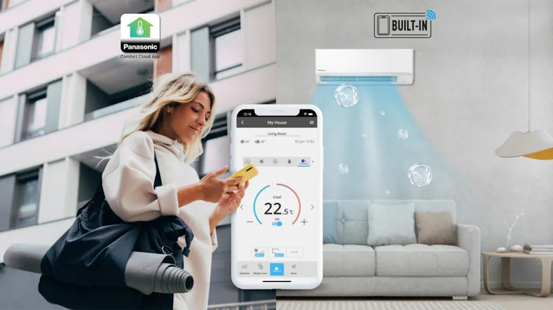 A person holding a smartphone displaying the Panasonic Comfort Cloud App stands next to a living room featuring an air conditioner with built-in Wi-Fi A person holding a smartphone displaying the Panasonic Comfort Cloud App stands next to a living room featuring an air conditioner with built-in Wi-Fi