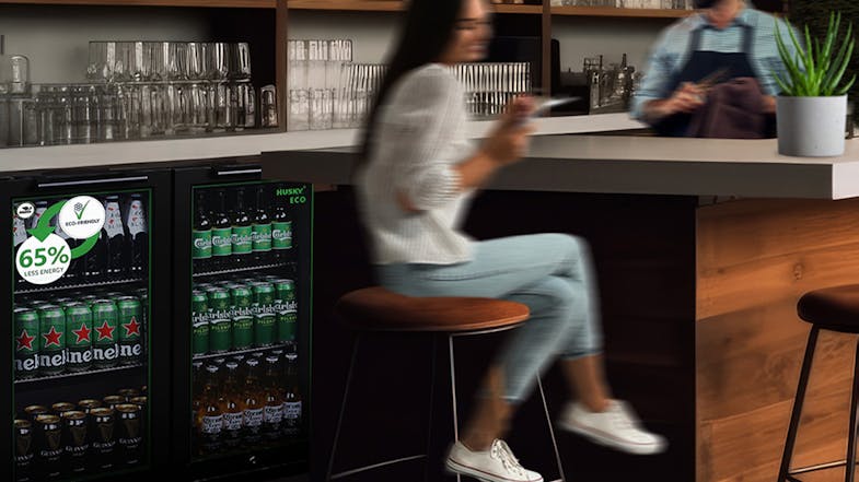 A commercial bar environment with the triple‑door fridge built into cabinetry, filled with cans and bottles A commercial bar environment with the triple‑door fridge built into cabinetry, filled with cans and bottles