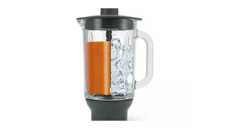 Glass blender jug filled with orange liquid and ice Glass blender jug filled with orange liquid and ice