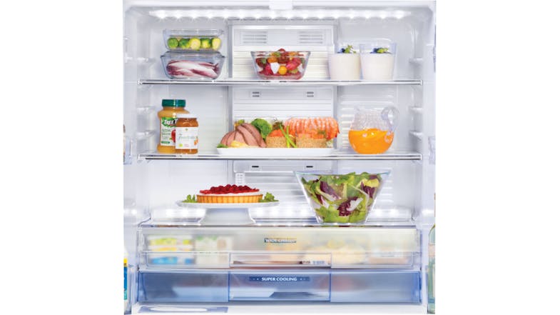 Interior view of a fridge showing organised shelves with fresh vegetables, fruits, desserts, juice, and a salad bowl Interior view of a fridge showing organised shelves with fresh vegetables, fruits, desserts, juice, and a salad bowl