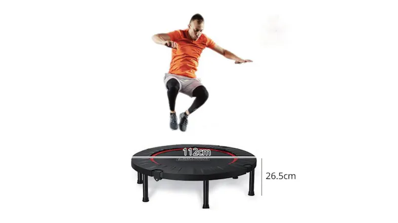 A person jumping above a round fitness trampoline, with dimensions of 112 cm in width and 26.5 cm in height shown A person jumping above a round fitness trampoline, with dimensions of 112 cm in width and 26.5 cm in height shown