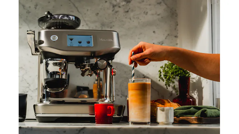 A person stirs a layered iced coffee. A person stirs a layered iced coffee.