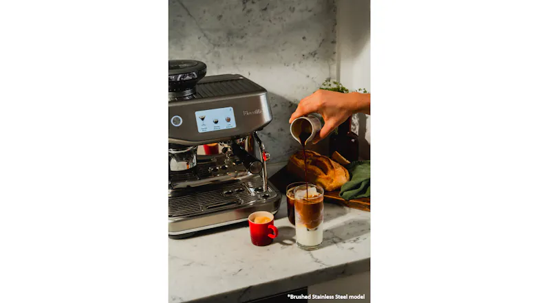 A person pours espresso from a white pitcher. A person pours espresso from a white pitcher.